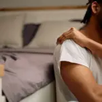 Person experiencing shoulder pain while lying in bed at night