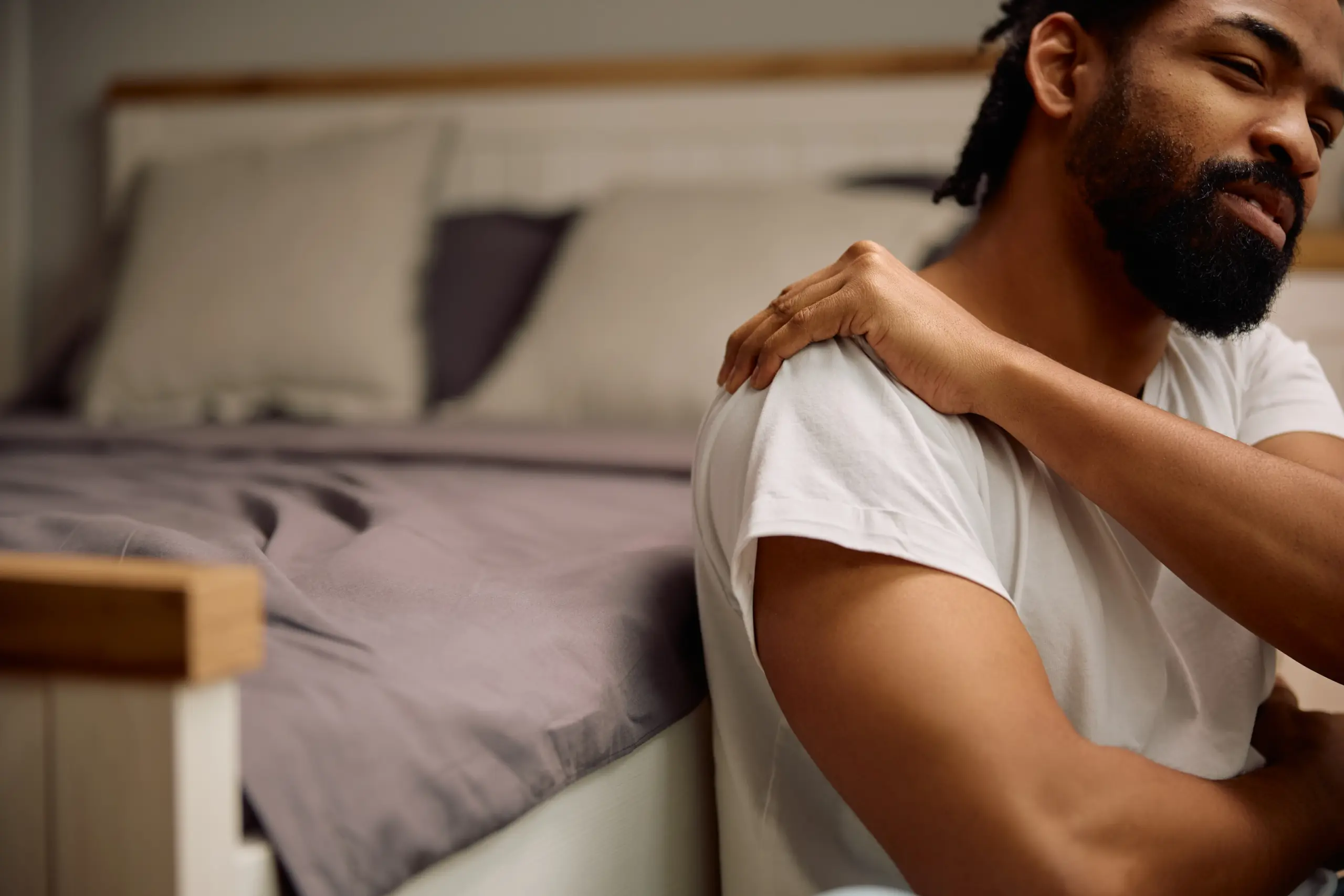 Person experiencing shoulder pain while lying in bed at night